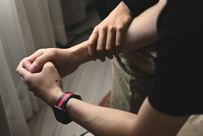 Person holding another’s arm indoors, illustrating social cues and moments of awkward or legendary cringe.