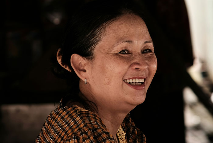 Smiling woman wearing checkered shirt, illustrating moments of misread social cues and creating legendary cringe.