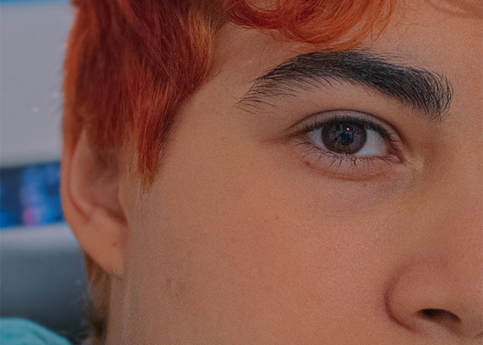 Close-up of a young person's face with red hair showing a subtle expression in a socially awkward situation.