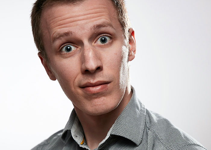 Young man with a confused expression illustrating socially awkward situations that are both painful and funny to experience.