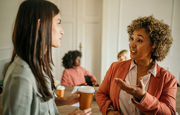 Two women having a serious conversation over coffee, depicting drama between moms after a child's birthday party incident.