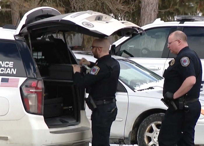 Two police officers near a forensic vehicle at a crime scene related to a haunting 911 call investigation.
