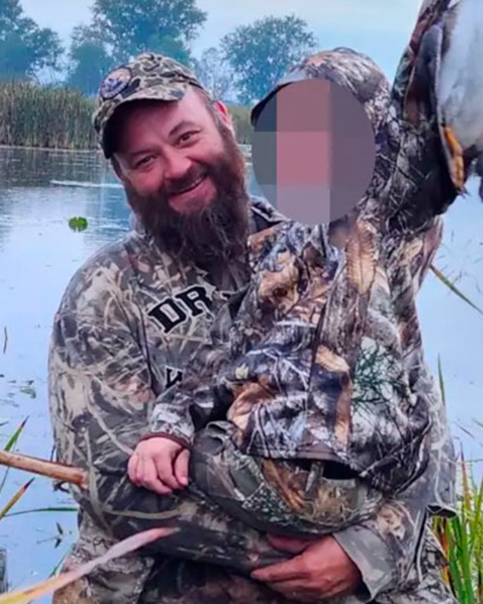 Man in camouflage holding child with blurred face near water, related to Mormons raising funds for Michigan church attacker.