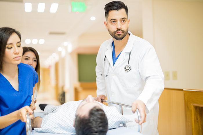 Doctor and nurses urgently moving a patient on a stretcher in hospital corridor, illustrating self-diagnosed health errors.