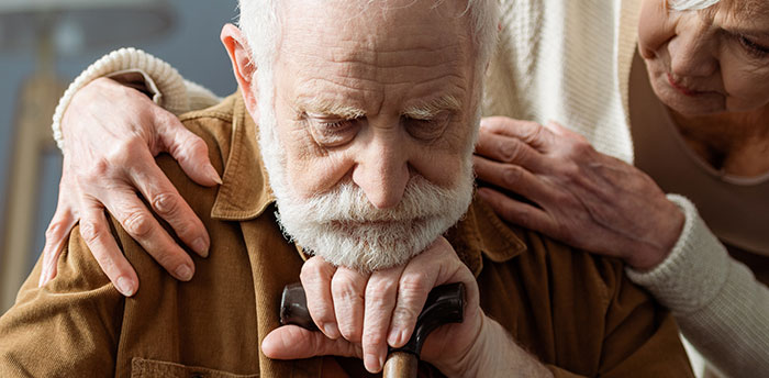 Older man leaning on cane with concerned woman comforting him, illustrating self-diagnosis and medical misunderstanding.