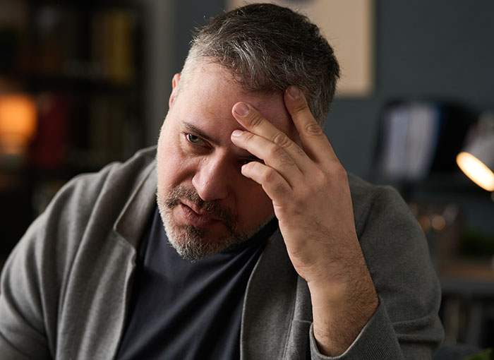 Middle-aged man looking worried and stressed, holding his forehead, illustrating self-diagnosis mistakes.