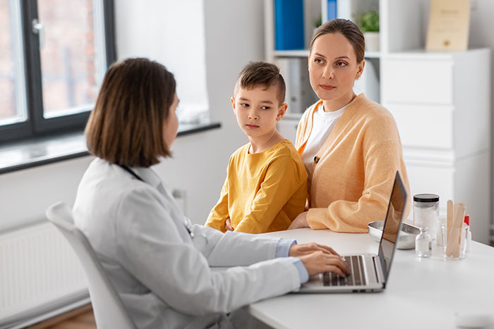 Mother and son with doctor in consultation, highlighting sibling of autistic and epileptic children facing neglect challenges.
