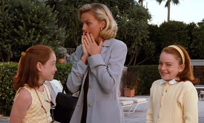 Two twins smiling near a woman reacting with surprise, representing group Halloween costume and stepmom inclusion debate.