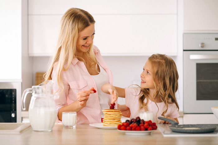 Sister vents about useless brother while teaching him a lesson, sharing a playful moment in the kitchen with pancakes and berries.