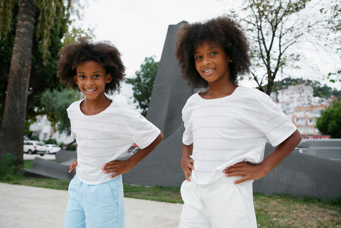 Two multilingual children smiling confidently outdoors, showcasing the theme of catching folks gossiping in secret languages.