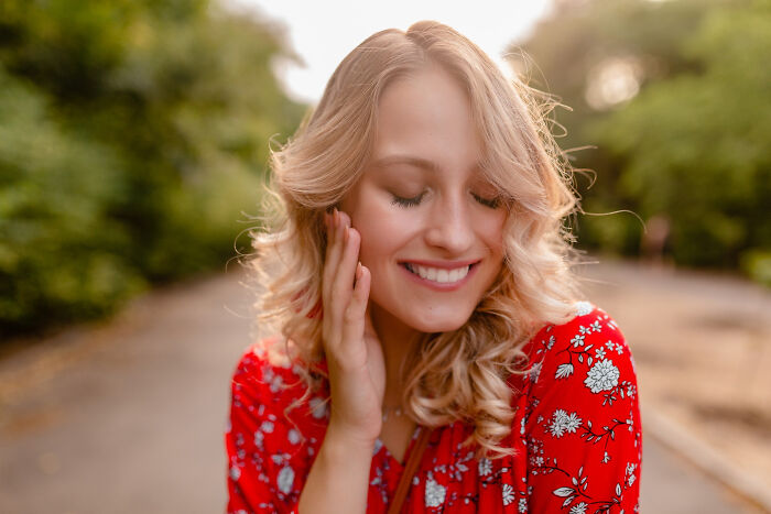 Young woman smiling outdoors, capturing the essence of multilinguals catching gossip in secret languages.