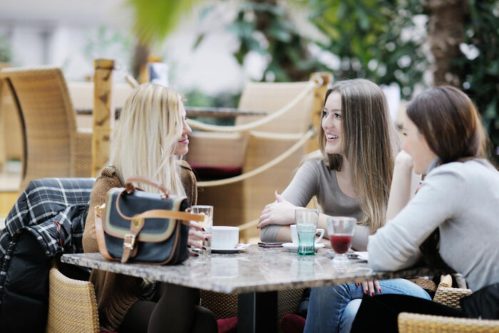Three multilingual women sitting at a café table chatting and catching gossip in secret languages they understood perfectly.