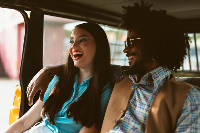 Two multilingual friends laughing and chatting inside a car, catching gossip in secret languages they understand perfectly.