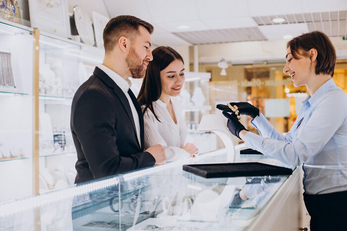 Couple at jewelry store counter talking to salesperson, illustrating multilinguals catching gossip in secret languages.