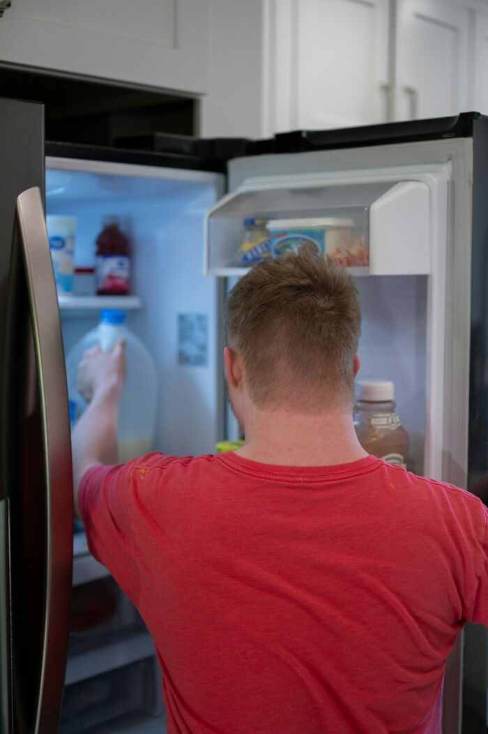 Man in a red shirt reaching into a fridge, illustrating a moment of karma striking with zero mercy concept.