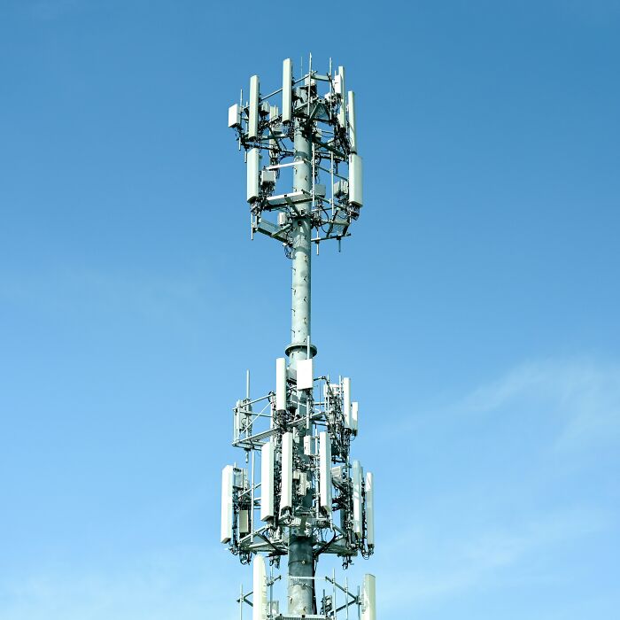 Cell tower under a clear blue sky representing unexplainable creepy things people have experienced in modern settings.