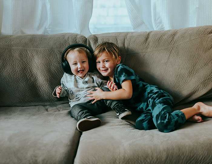 Two young kids sitting and playing on a couch, highlighting sibling care and family dynamics after mom abandonment.