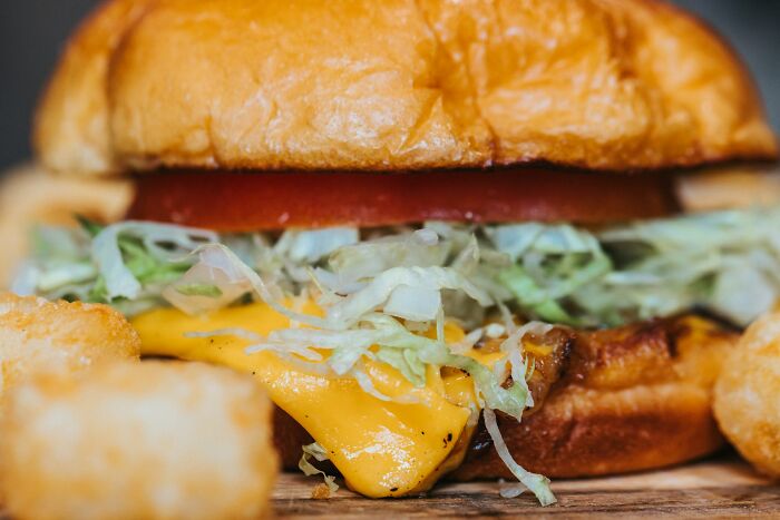 Close-up of a cheeseburger with lettuce and tomato, illustrating strange and dumb health hacks shared by patients.