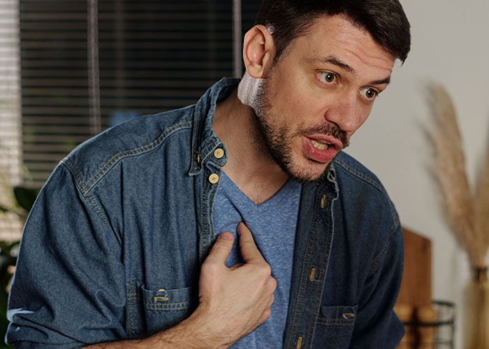Man in a denim shirt looks frustrated while discussing HOA board member refusing to follow pet ownership rules.