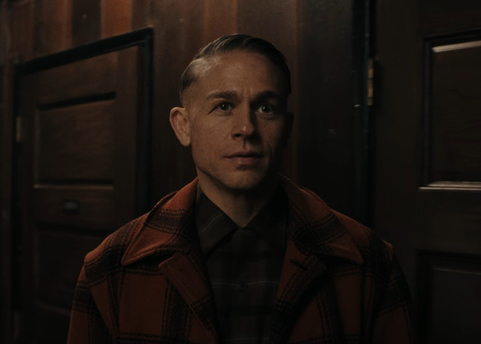 Man in a checkered coat standing indoors in a dimly lit room, related to Netflix's Monster The Ed Gein story details.