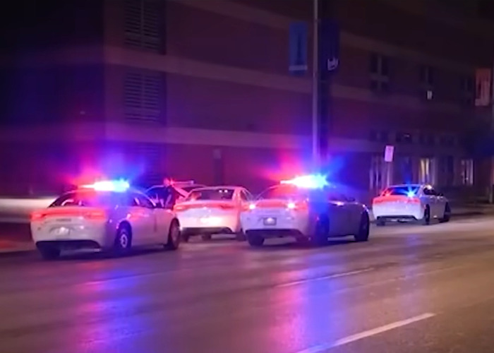 Police cars with flashing lights surround a vehicle on a dimly lit street during disturbing Mark Sanchez footage incident.