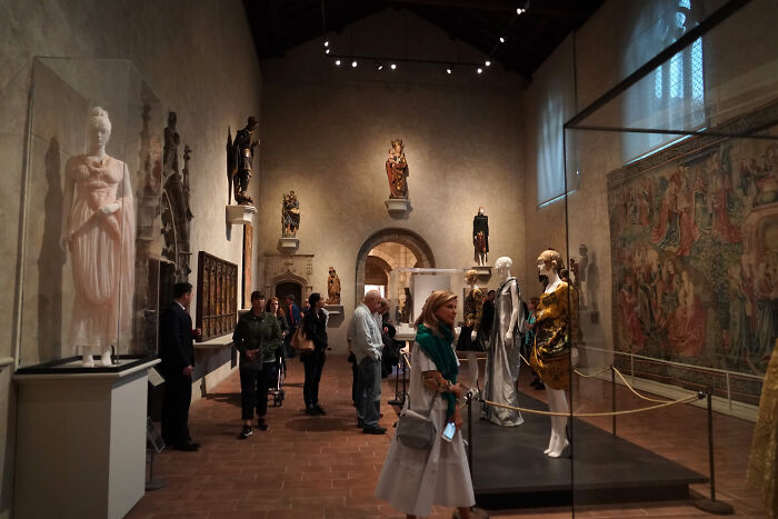 Visitors exploring an art gallery with sculptures and tapestries, illustrating 24 loopholes to start taking advantage of now.