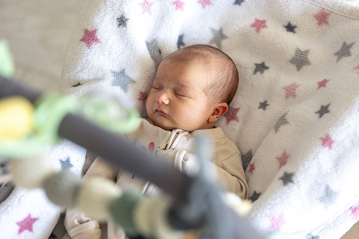 Sleeping baby wrapped in a soft star-patterned blanket highlighting burnt-out wife asking husband to feed the baby. Sleeping baby wrapped in a soft star-patterned blanket highlighting burnt-out wife asking husband to feed the baby.