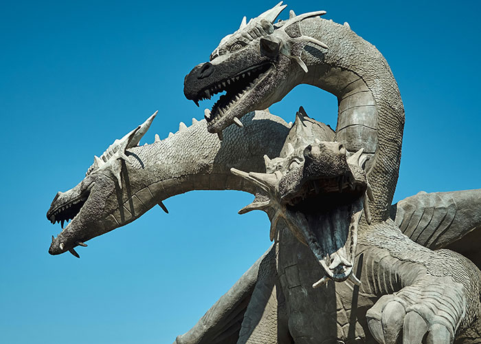Three-headed dragon statue under clear blue sky representing red flags in relationships and warning signs women noticed after breakups