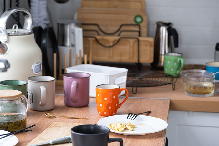 Cluttered kitchen countertop with various mugs, plates, and utensils, illustrating relationship red flags unnoticed by women.
