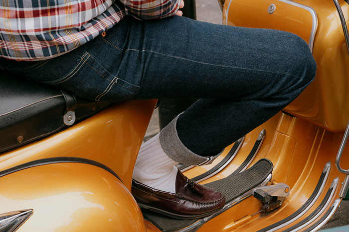 Person wearing jeans and loafers sitting on a vintage yellow scooter, illustrating subtle relationship red flags.