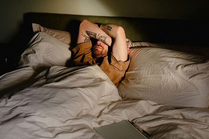 Man lying in bed covering his face, illustrating red flags in relationships women didn’t realize until after ending them.