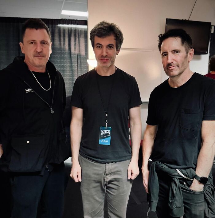 Tres hombres vestidos de negro en un ambiente interior, representando un tema de metraje encontrado inquietante y nightmarish.