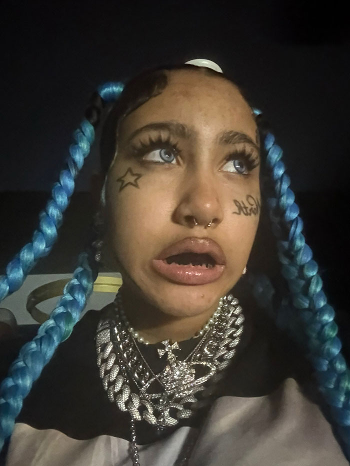 Young woman with blue braided hair and face tattoos, highlighting concerns about North's online life and new alarming look.
