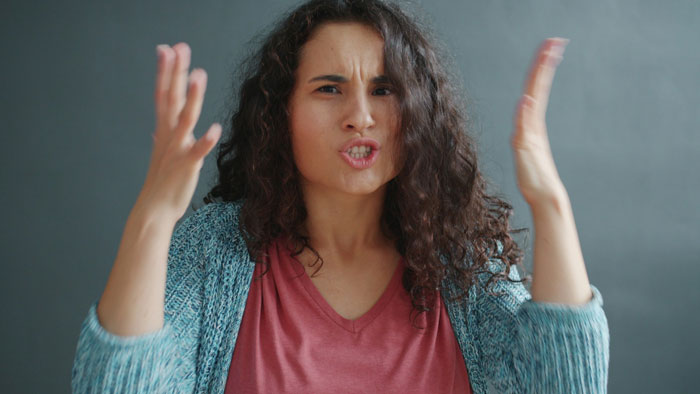 Frustrated woman with curly hair gesturing angrily, expressing tension related to ancestry tests and family conflict. Frustrated woman with curly hair gesturing angrily, expressing tension related to ancestry tests and family conflict.
