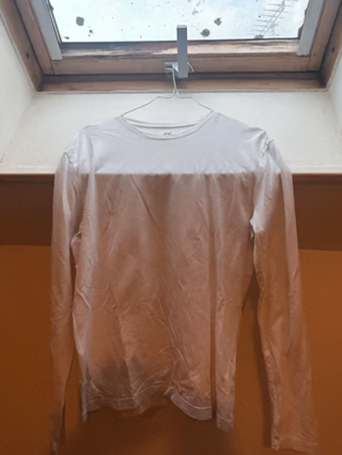 White long-sleeve shirt hanging in front of a window with light creating a surreal unphotoshopped effect.