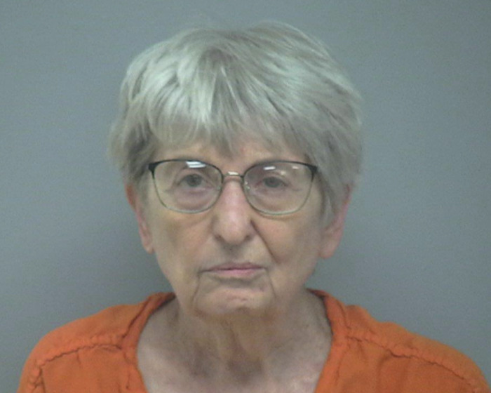82-year-old woman in glasses and orange top, linked to fatal attack on husband as revealed by handwritten notes.