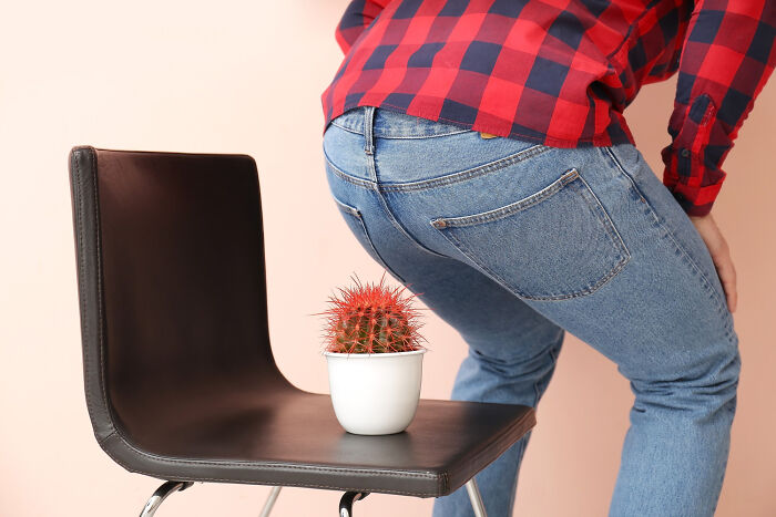 Man in jeans and red plaid shirt about to sit on chair with a small cactus symbolizing patients brushing off terrifying symptoms.