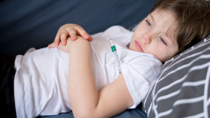 Sick child lying on couch with thermometer, illustrating patients brushing off terrifying symptoms as normal to doctors.