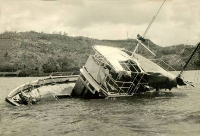 Partially sunken boat tilted in murky water near a shoreline, illustrating weird suspicious and fascinating things in the ocean.