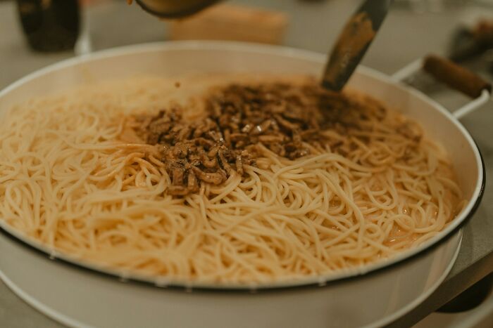 Shrimp jello dish served in a round pan with cooked noodles and small shrimp pieces on top in a home setting.