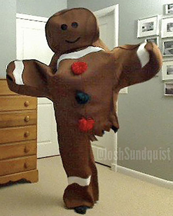 One-legged man in a creative gingerbread Halloween costume posing indoors with arms outstretched and a smiling face design.