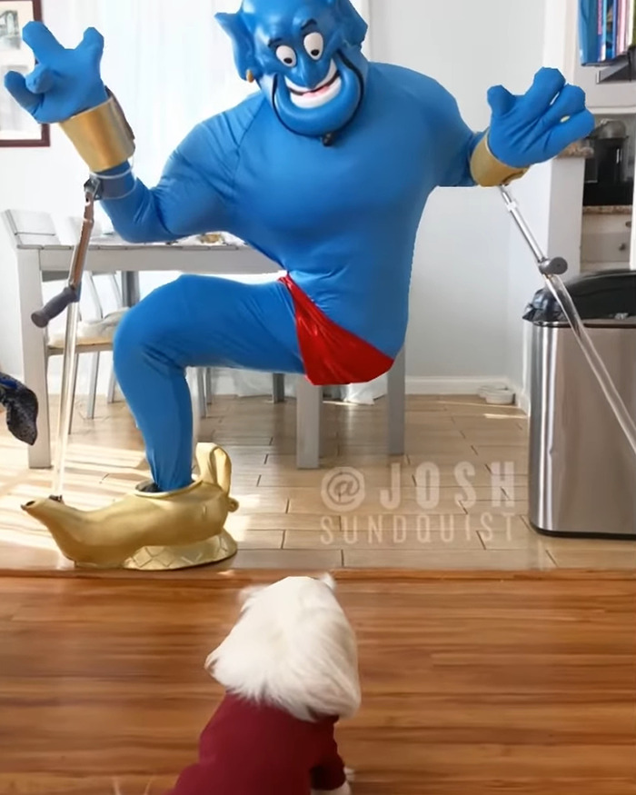 One-legged man in a blue genie costume with crutches posing humorously indoors for Halloween celebration.