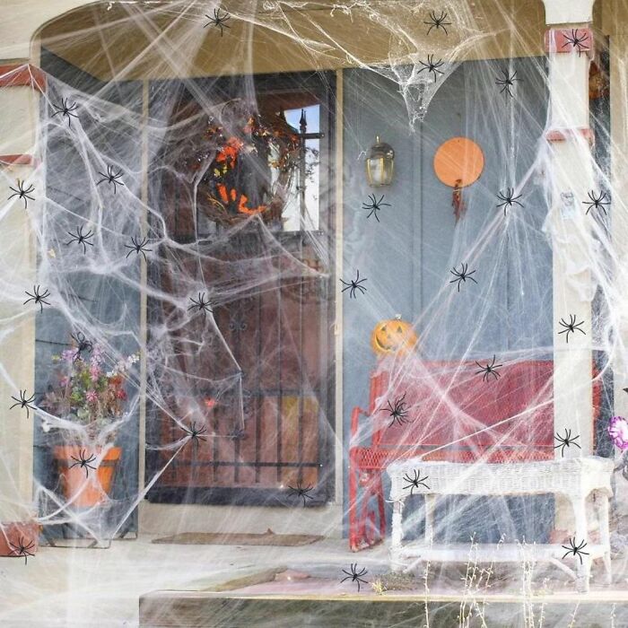 Front porch covered in spider webs and decorated with Halloween pumpkins, showcasing outdoor Halloween decorations.