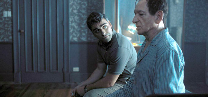 Two men sitting and talking in a dimly lit room, a scene from movies based on true stories that feel impossible to believe