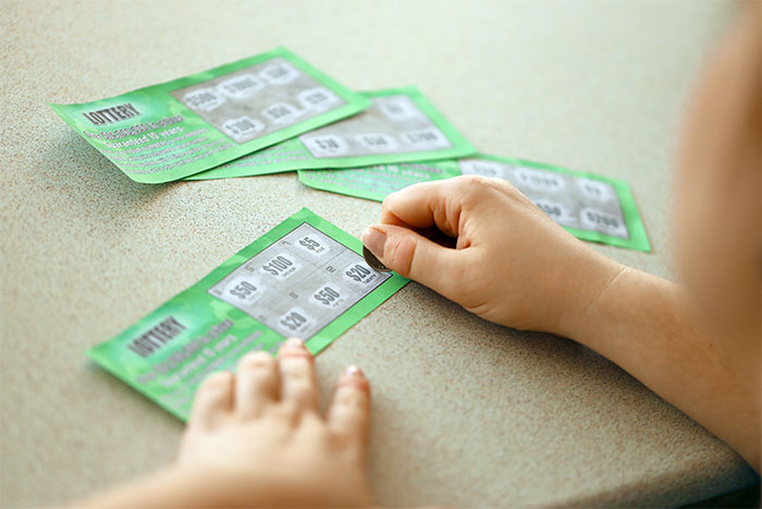 Child scratching lottery tickets at a table, illustrating young people's misunderstanding of credit card free money concepts.
