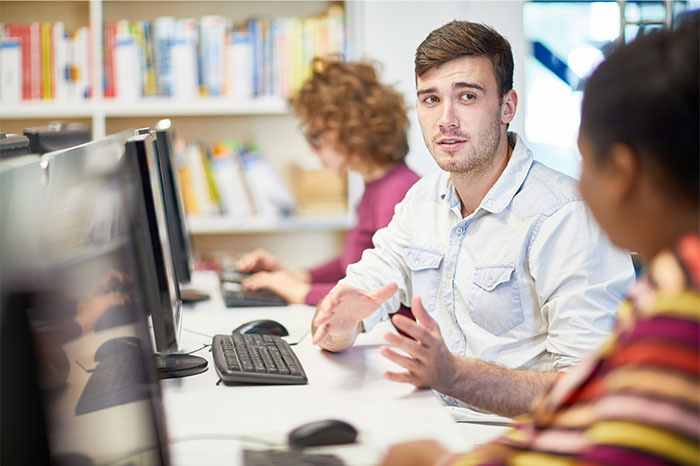 Young people discussing clueless things while using computers in a modern library setting.