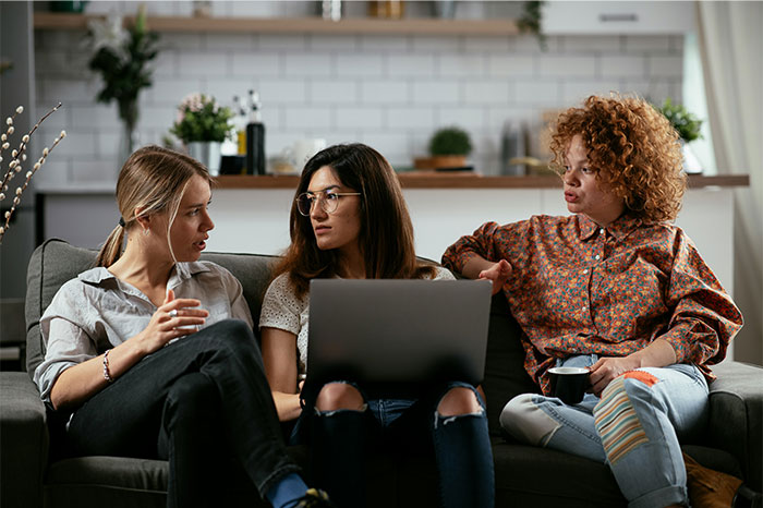 Three young people discussing on a couch with a laptop, illustrating clueless things young people have said.