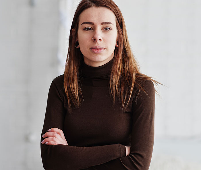 Young woman with serious expression and crossed arms, setting a boundary about disabled brother&rsquo;s care.