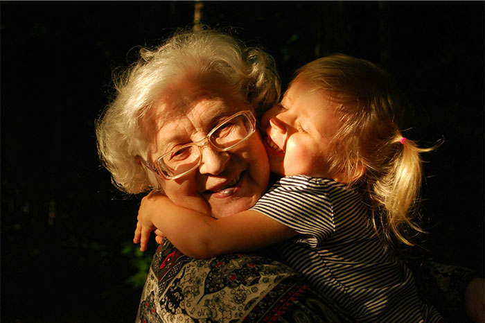 Elderly woman smiling warmly as a young child hugs her, illustrating parents sharing baby names they regret giving.