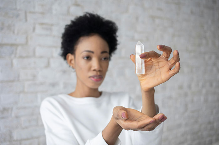 Woman holding and examining a clear crystal, illustrating focus and contemplation about baby names parents regret choosing.